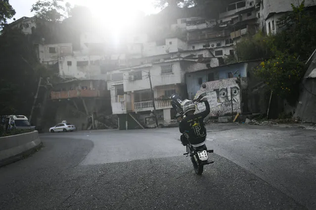 Motorcycle stuntman Pedro Aldana performs a wheelie on his motorbike as he rides to an exhibition along the old highway from Caracas to La Guaira, Venezuela, Sunday, January 10, 2021. Aldana, who prefers his show name “Crazy Pedro”, dares to beat the odds and put on exhibitions of speed and agility with a crew of like-minded daredevils atop their motorcycles. (Photo by Matias Delacroix/AP Photo)