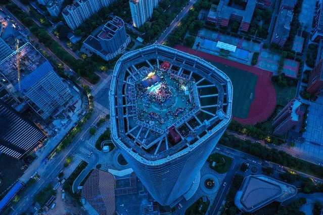 This aerial photo taken on June 28, 2023 shows people listening to a band playing music on the top of a building in Nanchang, in China's central Jiangxi province. (Photo by AFP Photo/China Stringer Network)