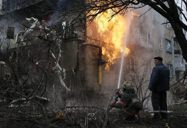 A firefighter works to extinguish a fire at a residential block, which was damaged by a recent shelling according to locals, on the outskirts of Donetsk, eastern Ukraine February 9, 2015. (Photo by Maxim Shemetov/Reuters)