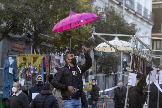 A stall-holder sets up his display in the Rastro flea market in Madrid, Spain, Sunday, November 22, 2020. Madrid's ancient and emblematic Rastro flea market reopened Sunday after a contentious eight-month closure because of the COVID-19 pandemic that has walloped the Spanish capital. (Photo by Paul White/AP Photo)