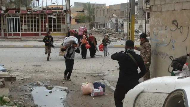Iraqi security forces and pro-government Sunni tribal fighters help trapped civilians to cross from neighborhoods under control of Islamic State group to neighborhoods under control of Iraqi security forces in Ramadi city,Iraq January 4, 2016. (Photo by Reuters/Stringer)