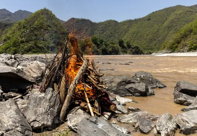 The burning pyre of Pramila Devi, 36, who died from complications related to the coronavirus disease (COVID-19), is seen during her cremation on the banks of the river Ganges in Pauri Garhwal in the northern state of Uttarakhand, India, May 24, 2021. (Photo by Danish Siddiqui/Reuters)