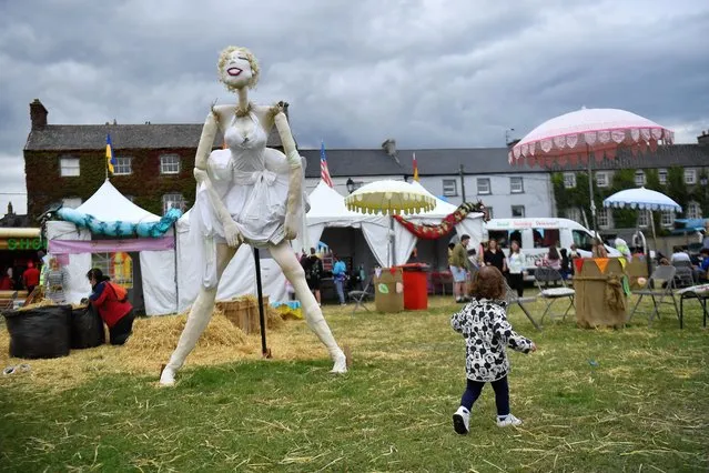 A child walks past a Marilyn Monroe themed scarecrow entered into the Ireland scarecrow championship during the Durrow Scarecrow Festival, in Durrow, Ireland on July 27, 2022. (Photo by Clodagh Kilcoyne/Reuters)