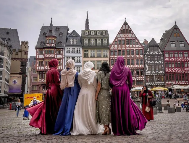 A bride, center, and her friend pose for pictures after a wedding in the town hall on the Roemerberg square in Frankfurt, Germany, Friday, June 25, 2021. (Photo by Michael Probst/AP Photo)