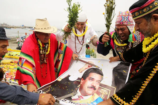 Peruvian shamans holding a poster of Venezuelan President Nicolas Maduro perform a ritual of predictions for the new year at Pescadores beach in Chorrillos, Lima, Peru, December 29, 2016. (Photo by Mariana Bazo/Reuters)