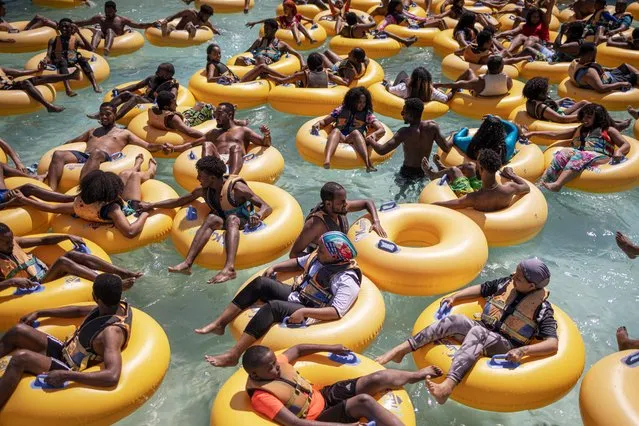 Vacationers play with inflatable donuts at a water park in Bishoftu on December 3, 2023. Just 40 kilometres outside Addis Ababa in the Oromia Region, Bishoftu is known for the number of crater lakes and its resorts, which makes it one of the premium leisure spots in the vicinity of the Ethiopian capital. (Photo by Michele Spatari/AFP Photo)