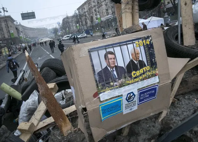Portraits of Ukrainian President Viktor Yanukovich and Prime Minister Mykola Azarov are seen at a barricade during a rally in central Kiev December 20, 2013. Ukrainian President Viktor Yanukovich on Thursday criticised opposition leaders, who have brought tens of thousands of protesters onto the streets, for harbouring their own political ambitions and conducting “revolutionary” actions. (Photo by Gleb Garanich/Reuters)