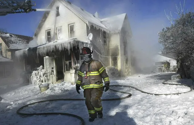 A firefighter walks past an ice-encrusted home after an early morning house fire Wednesday, January 30, 2019 in St. Paul, Minn. Firefighters were called to the house fire in the North End shortly after 4:15 a.m. The air temperature was 27 degrees below zero Wednesday morning, with windchills at 52 degrees below zero. No injuries were reported. (Photo by Jean Pieri/Pioneer Press via AP Photo)