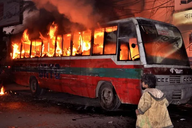 A young Bangladeshi child walks past a passenger bus torched by opposition party supporters ahead of the general elections in Dhaka, Bangladesh, Thursday, January 2, 2014. Bangladesh's main opposition Bangladesh Nationalist Party (BNP) and its alliances are boycotting the parliamentary elections set for January 5 demanding for an independent caretaker government to oversee the polls. (Photo by AP Photo)