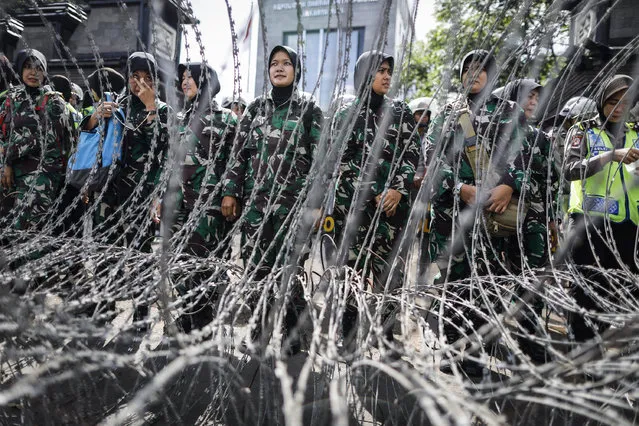 Indonesian military personnel stand behind barb-wire during a protest outside the police headquarters in Jakarta, Indonesia, 23 January 2017. More than a thousand supportes staged a protest as Rizieq arrived at the police headquarters for questioning over the allegations of defaming Indonesia's national symbols. (Photo by Mast Irham/EPA)