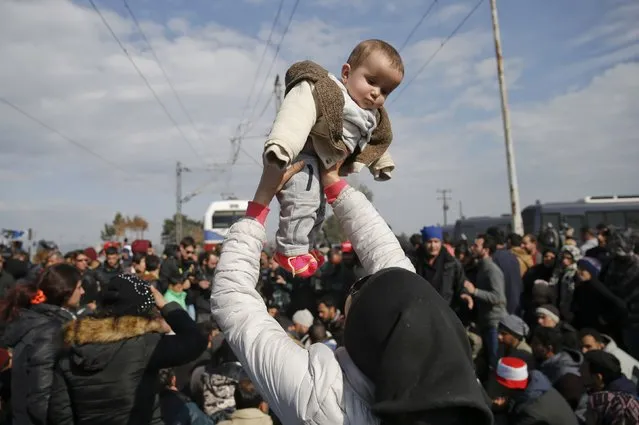 A migrant holds her baby as she blocks the railway track at the Greek-Macedonian border, near the village of Idomeni, Greece March 3, 2016. (Photo by Marko Djurica/Reuters)