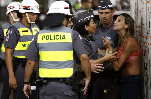 A demonstrator argues with policewomen after she turned up her shirt and was taken out from a protest to demand the resignation of Brazilian President Dilma Rousseff, on March 13, 2016 in Paulista Avenue in Sao Paulo. Protesters, many draped in the Brazilian national flag, poured into the streets of Brasilia and Rio de Janeiro on Sunday at the start of mass demonstrations seeking to bring down President Dilma Rousseff. Authorities in Sao Paulo, Brazil's biggest city and an opposition stronghold, said they were bracing for a million protesters. (Photo by Miguel Schincariol/AFP Photo)