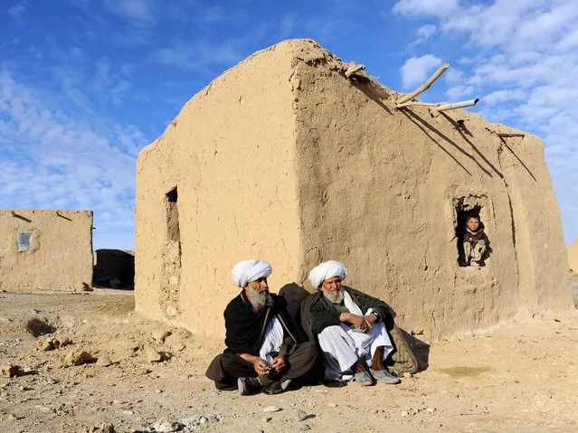 Afghan residents sit outside a hut on the outskirts of Herat on February 12, 2014. Some nine million Afghans or 36 percent of the population are living in “absolute poverty” while another 37 percent live barely above the poverty line, according to a UN report. (Photo by Aref Karimi/AFP Photo)