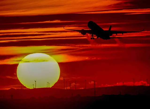 An aircraft takes off at the international airport in Frankfurt, Germany, as the sun sets Monday, October 4, 2021. (Photo by Michael Probst/AP Photo)