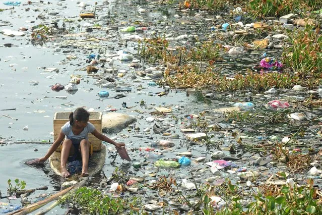 A woman paddles in a makeshift boat as she collects recyclable trash from a polluted river in Navotas city, Philippines May 6, 2015. (Photo by Ezra Acayan/Reuters)