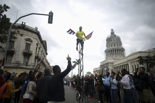 A man pedals a bicycle displaying the U.S. and Cuban flags near the Capitol, as people wait for an eventual visit of U.S. President Barack Obama to downtown Havana, March 21, 2016. (Photo by Alexandre Meneghini/Reuters)