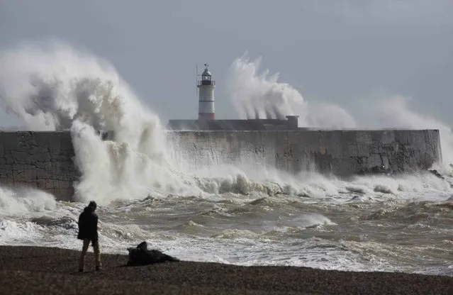 People watch waves crash against the harbour wall at Newhaven in southern Britain March 28, 2016. (Photo by Neil Hall/Reuters)