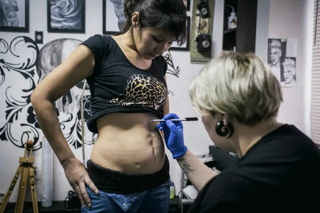 In this photo taken on Tuesday, December 6, 2016 tattoo artist Yevgeniya Zakhar works on a tattoo for Lyaysan, a victim of domestic violence, in Ufa, Russia. Yevgeniya Zakhar, a Russian tattoo artist from Ufa, a city about 1,200 kilometers (745 miles) east of Moscow, gives free tattoos to victims of domestic abuse, to cover their scars. (Photo by Vadim Braydov/AP Photo)
