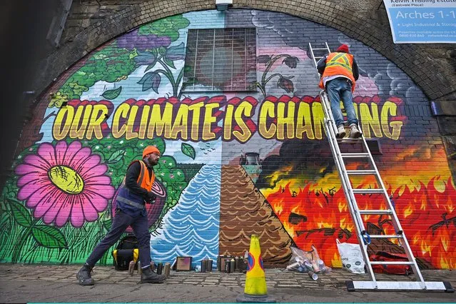 Artists paint a mural on a a wall next to the Clydeside Expressway near Scottish Events Centre (SEC) which will be hosting the COP26 UN Climate Summit later this month, on October 13, 2021 in Glasgow, Scotland. COP26 will officially begin on Sunday October 31 with the procedural opening of negotiations and finish on Monday November 12th. (Photo by Jeff J. Mitchell/Getty Images)