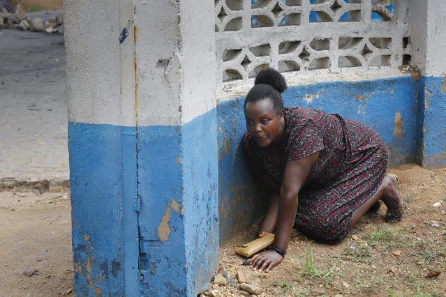 A woman takes cover as shots are fired by police officers as they face off with stone-throwing protesters, during an anti-government demonstration in Bujumbura, Burundi, 20 May 2015. Police officers fired shots and teargas canisters in running battles with protesters who demonstrated against Burundi's President Pierre Nkurunziza's bid for a third term. (Photo by Dai Kurokawa/EPA)