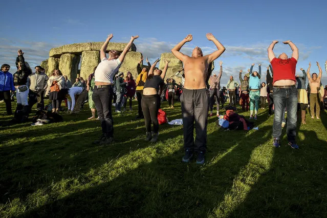 People offer salutations to the sun, at Stonehenge as crowds of people gather to celebrate the dawn of the longest day in the UK, in Wiltshire, England, Friday June 21, 2019. (Photo by Ben Birchall/PA Wire via AP Photo)
