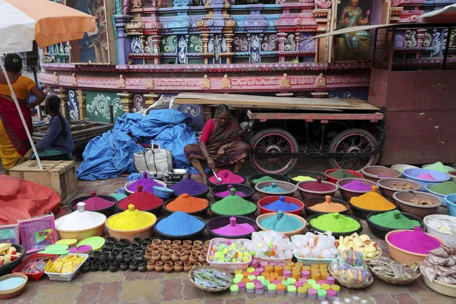 A vendor arranges colored powder while waiting for customers ahead of Sankranti festival in Hyderabad, India, Wednesday, January 12, 2022. People make rangoli a traditional art work of colored powder in front of their homes and fly kites during Sankranti. (Photo by Mahesh Kumar A./AP Photo)