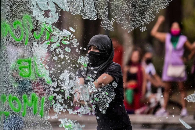 A woman breaks a glass at the entrance of Hidalgo metro station during a demonstration to commemorate the International Women's Day in Mexico City, on March 8, 2021. (Photo by Pedro Pardo/AFP Photo)