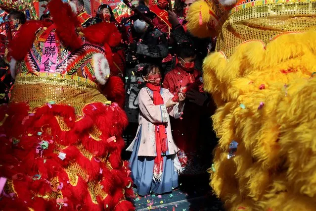 A girl in traditional costume stands amid lion dancers during a Chinese Lunar New Year, Year of the Tiger, cultural celebration in the Chinatown neighborhood of Manhattan in New York City, New York, U.S., February 1, 2022. (Photo by Mike Segar/Reuters)