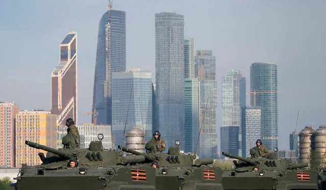 Russian servicemen sit atop of Russian BMP-3 armoured personnel carriers before a rehearsal for the Victory Day parade, with the Moscow International Business Center also known as “Moskva-City” seen in the background, at a range in Moscow, Russia, May 5, 2016. (Photo by Maxim Shemetov/Reuters)