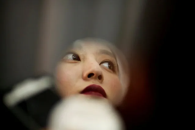 A model checks her make-up in a pocket mirror in the backstage area before the Shangshou Huatian fashion show by Ren Yi at China Fashion Week in Beijing, China, March 29, 2017. (Photo by Thomas Peter/Reuters)