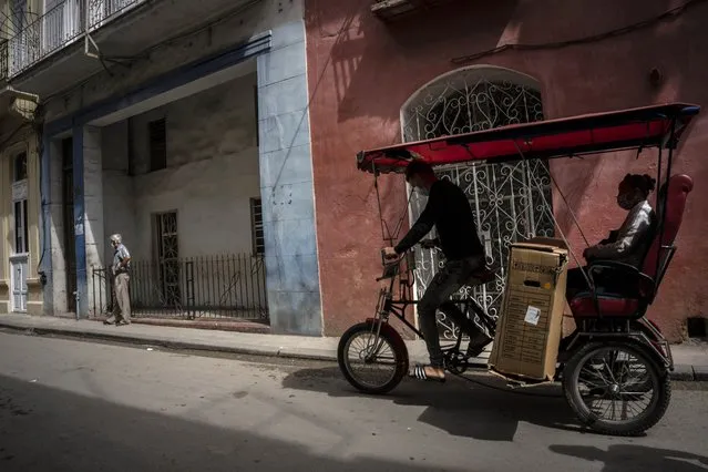 Wearing masks amid the COVID-19 pandemic, a man transports a customer on a bicycle taxi in Havana, Cuba, Wednesday, February 16, 2022. (Photo by Ramon Espinosa/AP Photo)