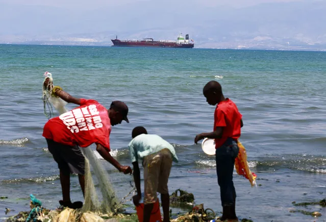 In this April 16, 2019 photo, residents fish while a tanker waits out in the bay to unload its cargo at the Thor terminal in Carrefour, a district of Port-au-Prince, Haiti. The current fuel crisis is helping push Haiti's economy dangerously close to recession. (Photo by Dieu Nalio Chery/AP Photo)