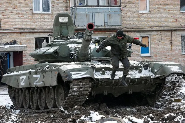 A service member of pro-Russian troops in uniform without insignia jumps off a tank with the letters “Z” painted on it outside a residential building which was damaged during Ukraine-Russia conflict in the separatist-controlled town of Volnovakha in the Donetsk region, Ukraine March 11, 2022. (Photo by Alexander Ermochenko/Reuters)
