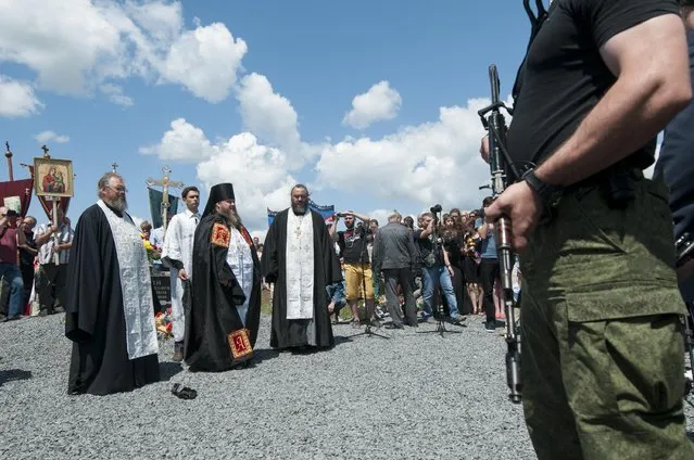 Orthodox priests attend a memorial ceremony at the crash site of the Malaysian Airlines MH17 plane near the village of Hrabove, eastern Ukraine, Friday, July 17, 2015. (Photo by Antoine E. R. Delaunay/AP Photo)