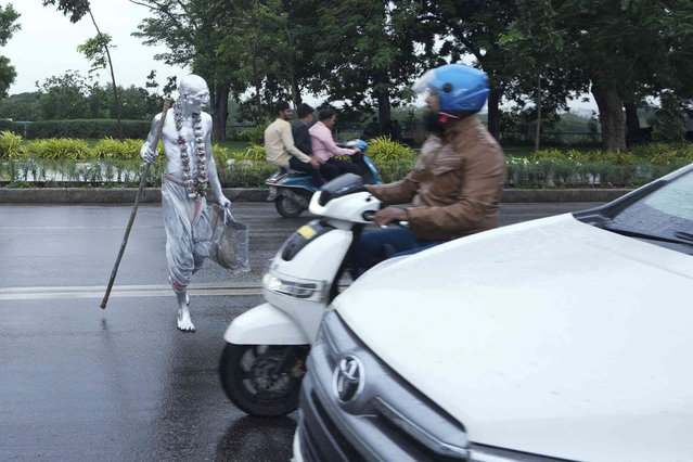 A man with body painted and dressed as Mahatma Gandhi crossing a road to seek alms in Hyderabad, India, Wednesday, July 24, 2024. (Photo by Mahesh Kumar A./AP Photo)