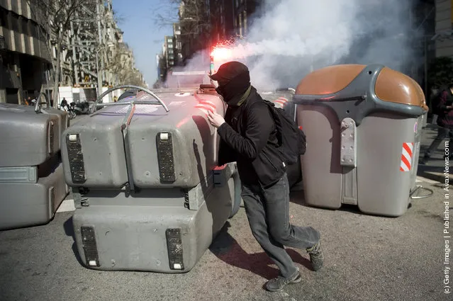 A student sets fire to garbage containers with a flare during a demonstration on February 29, 2012 in Barcelona