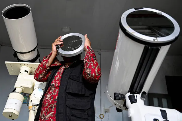 An observatory officer checks a telescope before looking for the moon to mark the start of Islam's holy month of Ramadan at Lhoknga beach in Aceh province on April 1, 2022. (Photo by Chaideer Mahyuddin/AFP Photo)
