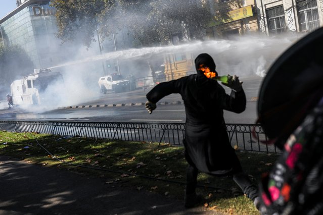 A person throws a Molotov cocktail as demonstrators clash with riot police during a May Day rally in Santiago, Chile on May 1, 2023. (Photo by Pablo Sanhueza/Reuters)