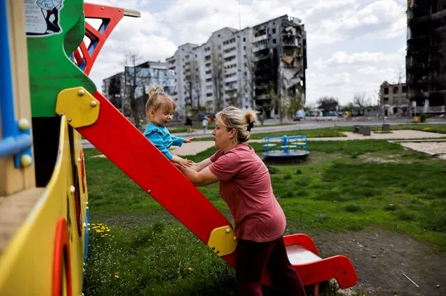 Inna Stefuryak, 42, holds her daughter Nina, 2, as she plays at the playground in front of a building, destroyed by the shelling, amid the Russian invasion of Ukraine, in Borodianka, Kyiv region, Ukraine, May 2, 2022. (Photo by Zohra Bensemra/Reuters)