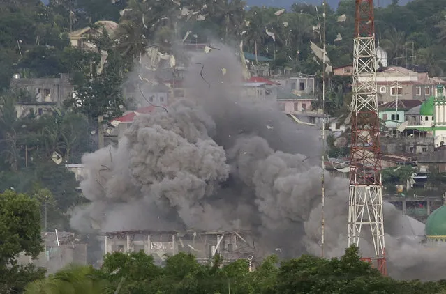 Debris fly as Philippine Air Force fighter jets bomb suspected locationss of Muslim militants as fighting continues in Marawi city, southern Philippines, Friday, June 9, 2017. It's unclear how many people remain trapped in Marawi as government troops battle Muslim militants led by the so-called “Maute” group but army officers have put the figure this week at anywhere from 150 to 1,000. (Photo by Aaron Favila/AP Photo)