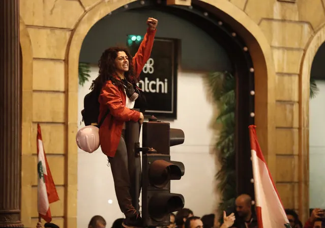An anti-government protesters stands on a traffic light, as she shouts slogans during a protest near the parliament square, in downtown Beirut, Lebanon, Sunday, December 15, 2019. (Photo by Hussein Malla/AP Photo)