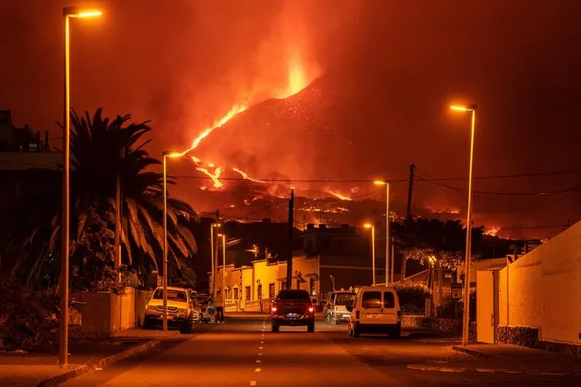A car drives through an empty street in the neighborhood of La Laguna as lava flows from the Cumbre Vieja Volcano on October 9, 2021 in La Palma, Spain. The Cumbre Vieja Volcano erupted on September 19, shutting down the airport twice due to the volcanic ash. The numerous lava flows destroyed hundreds of hectares, but also formed peninsulas of volcanic rock, extending the surface of the island. (Photo by Marcos del Mazo/Getty Images)