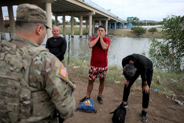 Three migrants from Cuba stand in front of a National Guardsman after crossing the Rio Grande river in Eagle Pass, Texas, Sunday May 22, 2022. Little has changed in what has quickly become one of the busiest corridors for illegal border crossings since a federal judge blocked pandemic-related limits on seeking asylum from ending Monday. (Photo by Dario Lopez-Mills/AP Photo)