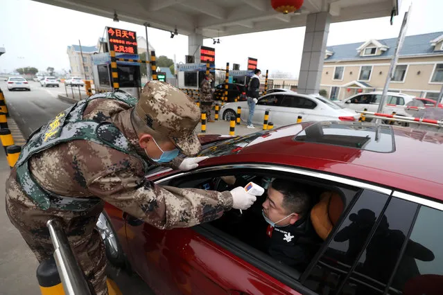 A militia member checks the body temperature of a driver on a vehicle at an expressway toll gate in Wuhan in central China's Hubei province, 23 January 2020, in a bid to contain the spread of the new coronavirus. (Photo by Yuan Zheng/EPA/EFE)