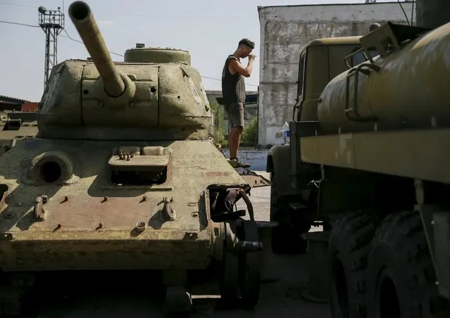 A worker stands at old soviet tank T-34 as he fixes military vehicle (R) at Phaeton museum in Zaporizhia, Ukraine, August 11, 2015. (Photo by Gleb Garanich/Reuters)