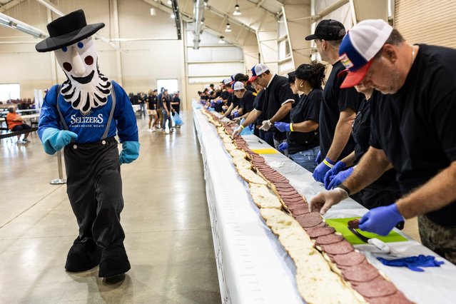 Seltzer's mascot looks on as volunteers assemble a 150-foot-long (45.7-meters-long) bologna sandwich  at the Lebanon Area Fair on Tuesday, July 25, 2023 in  Lebanon, Pa. Every footlong “bite” was sponsored at $100 per foot. The money was donated to Lebanon County Christian Ministries and their efforts to help people dealing with food insecurity in the Lebanon Valley. (Photo by Sean Simmers/The Patriot-News via AP Photo)