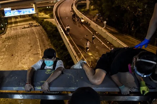 Protesters take a rope down from a bridge to a highway, to escape from Hong Kong Polytechnic University campus and from police, in Hung Hom district in Hong Kong on November 18, 2019. Dozens of Hong Kong protesters escaped a besieged university campus on November 18 by lowering themselves on a rope from a footbridge to a highway, AFP video showed. Once on the road they were seen being picked up by waiting motorcyclists. (Photo by Ye Aung Thu/AFP Photo)