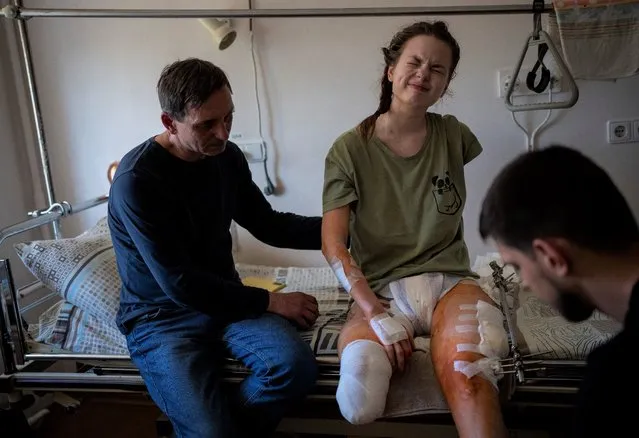 Nastia Kuzik, 21, reacts to pain while undergoing a rehabilitation session at a public hospital in Kyiv, Ukraine, Wednesday, May 4, 2022. In the morning on March 17, she went to her brother's house in Chernihiv, then on her way back was caught in a bombing. She lost her right leg below the knee and seriously injured her left leg. Has now been transported to Germany for further treatment. (Photo by Emilio Morenatti/AP Photo)