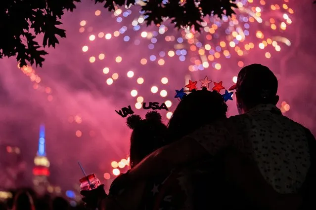 People watch the Macy's Fourth of July fireworks in New York City, New York, U.S., July 4, 2022. (Photo by Jeenah Moon/Reuters)