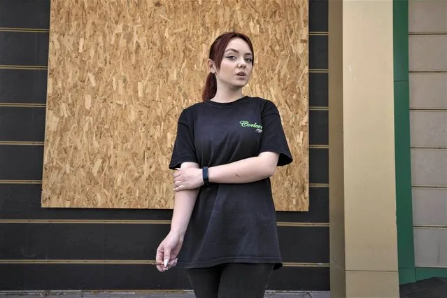 Eighteen-year-old waitress, Karina Smulska, who returned to her home town after fleeing, smokes a cigarette outside the restaurant she works, in Pokrovsk, eastern Ukraine, Wednesday, July 20, 2022. Tens of thousands of people from Donetsk region are returning to their rural or industrial communities close to the front line at considerable risk because they can't afford to live in safer places. (Photo by Nariman El-Mofty/AP Photo)